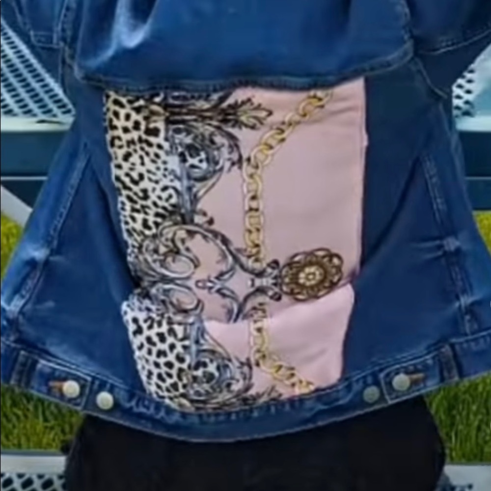 Denim jacket embellished with pink and leopard designer scarf.